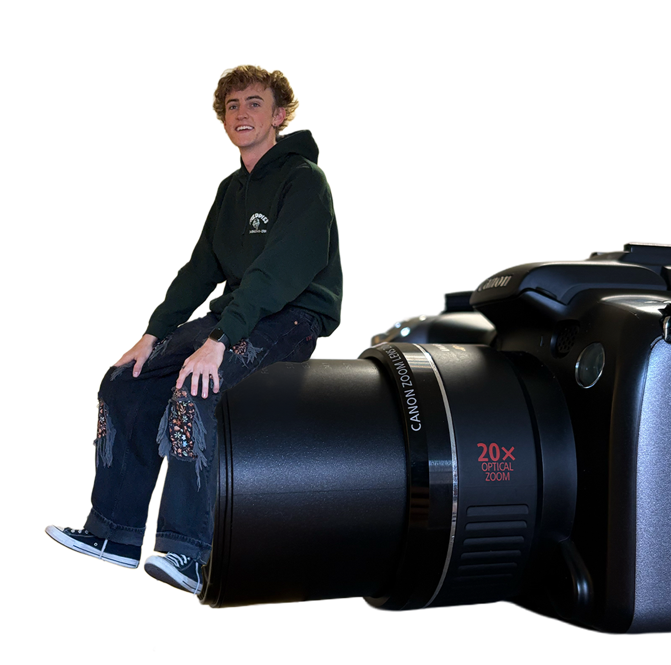 Kai sitting on a Canon camera, smiling at the camera