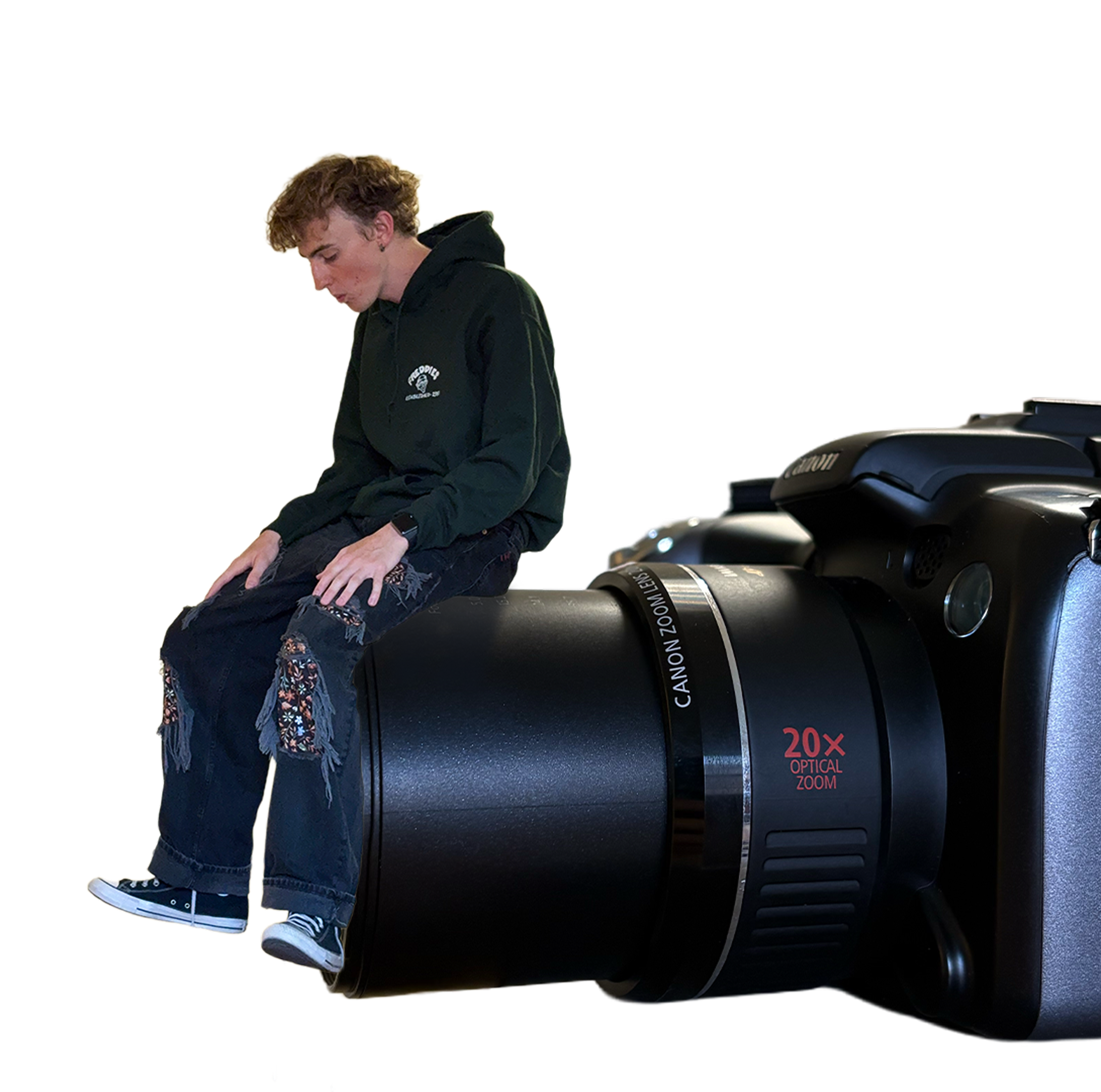 Kai sitting on a Canon camera, looking down at the lens
