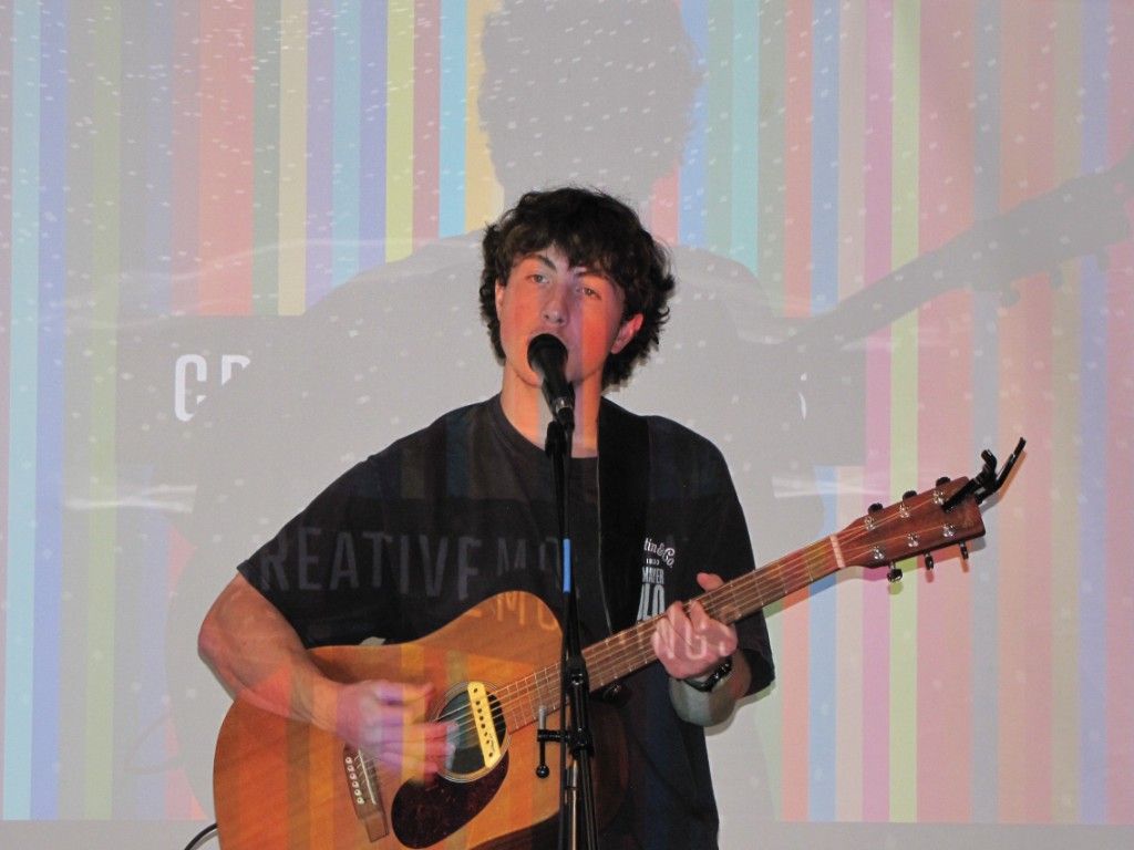 Young guitarist performing with his projected shadow on the striped backdrop