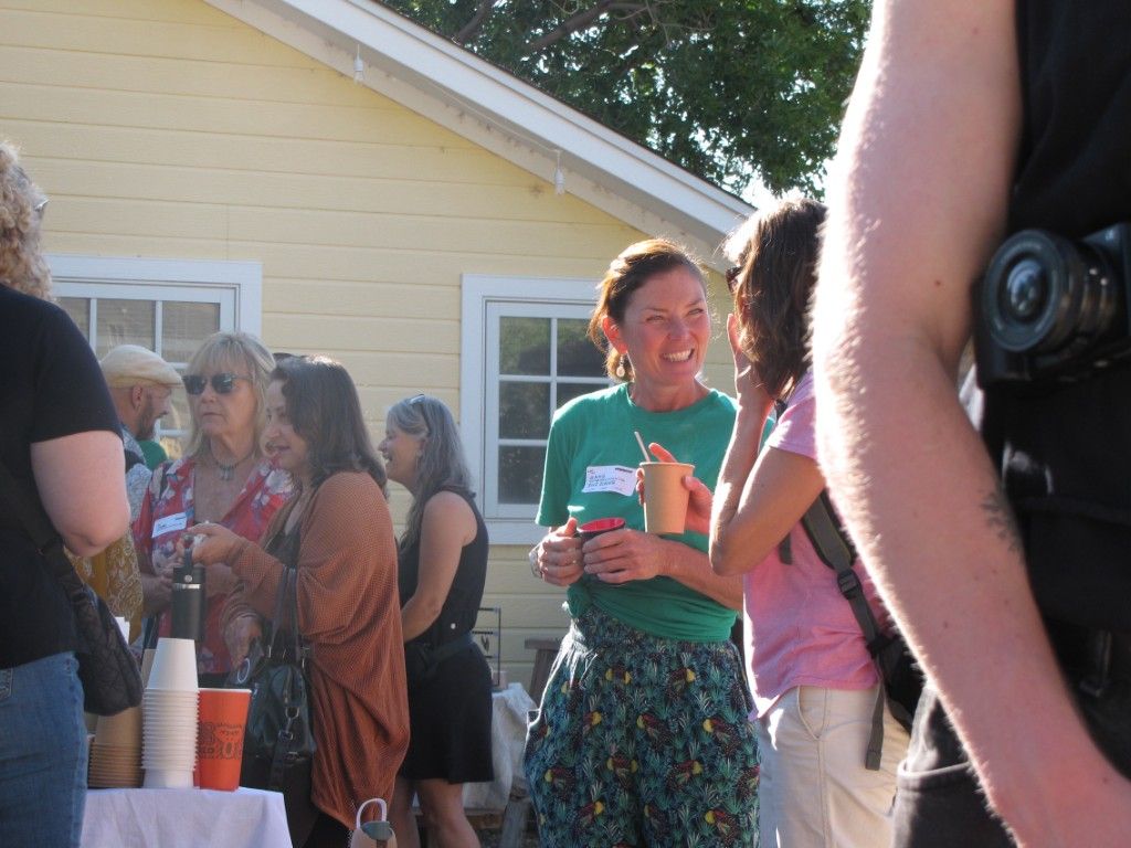 Attendees chatting over coffee in a sunny backyard