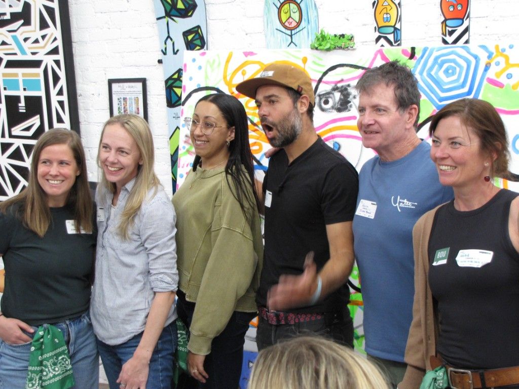 Group of attendees laughing in front of a colorful painted art wall