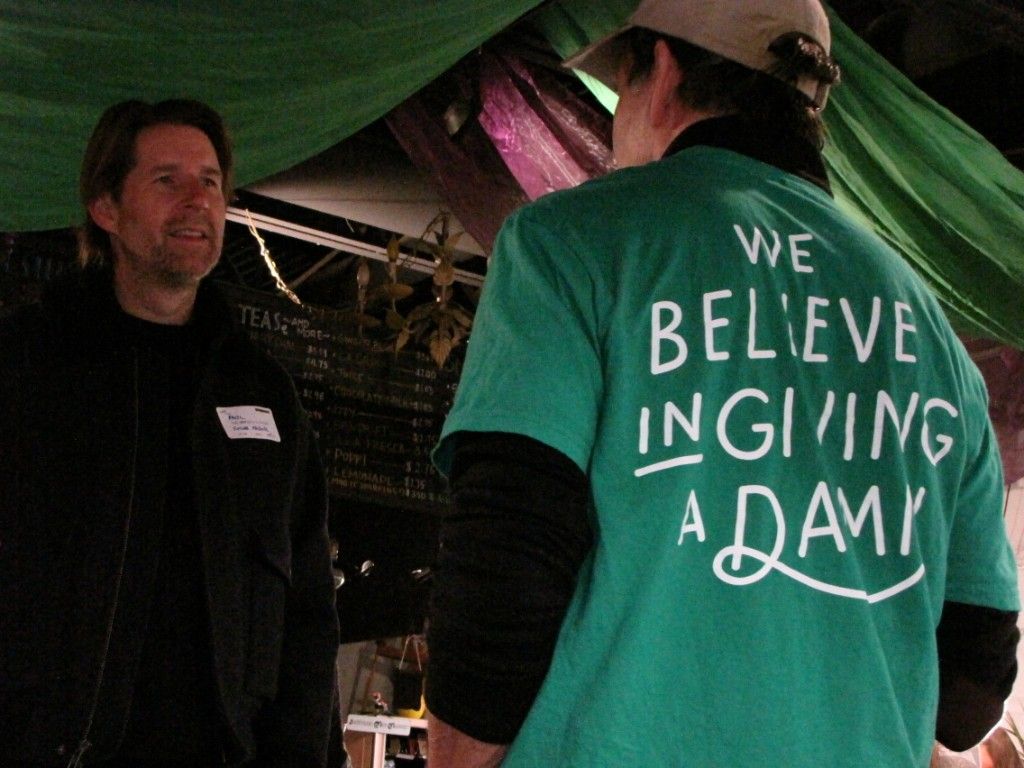 Volunteer in a We Believe in Giving a Damn shirt talking with an attendee