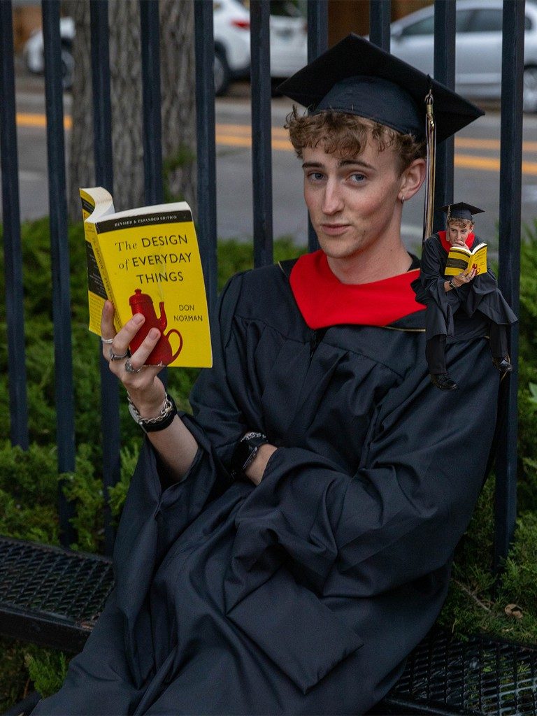Graduate reading The Design of Everyday Things with a miniature self on his shoulder