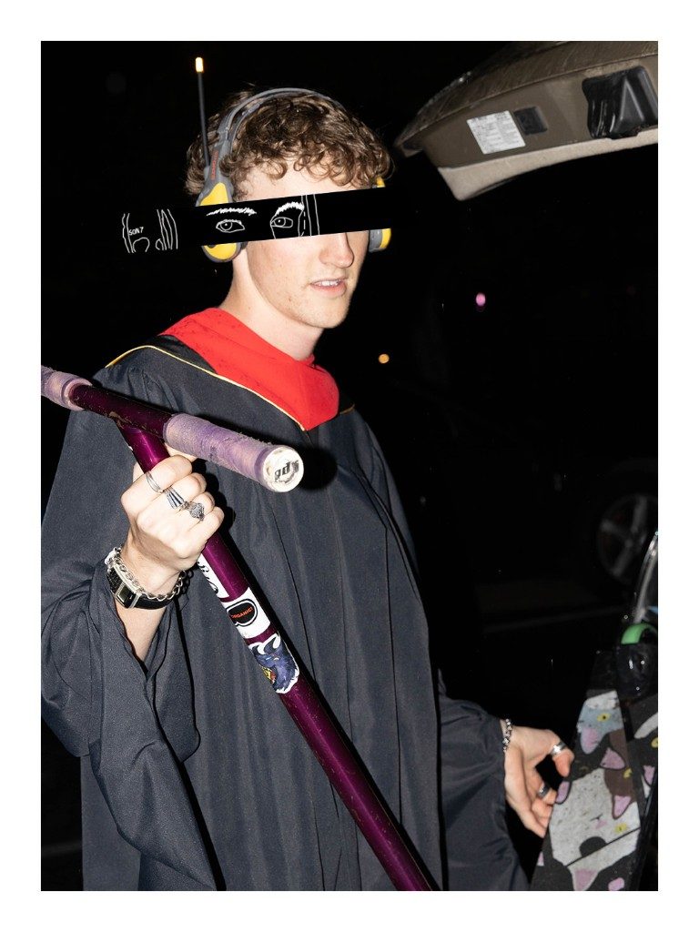 Graduate with headphones and drawn-on eyes holding a purple scooter