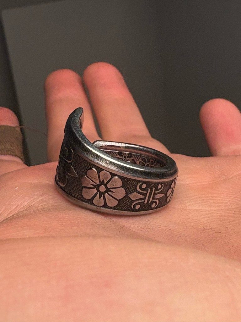 Floral silver spoon ring held in palm