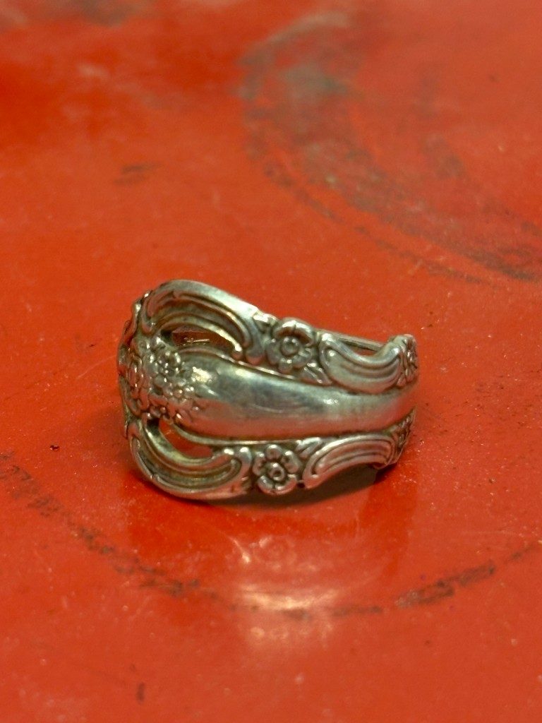 Floral scroll silver spoon ring on red surface