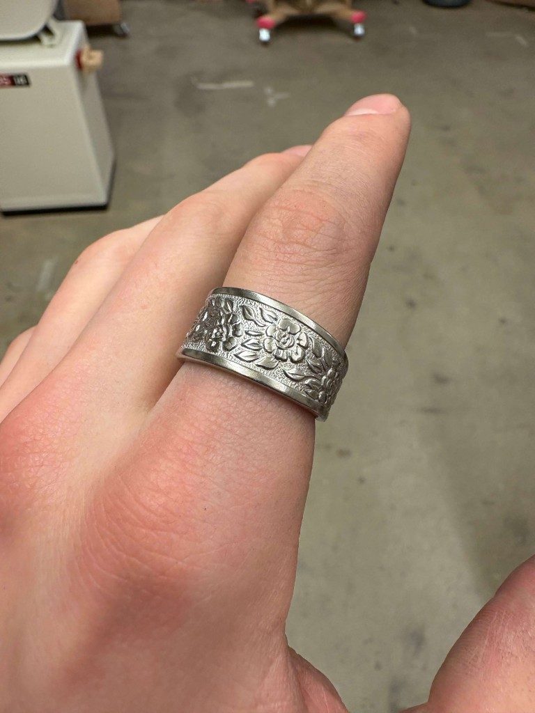 Floral embossed silver spoon ring on index finger