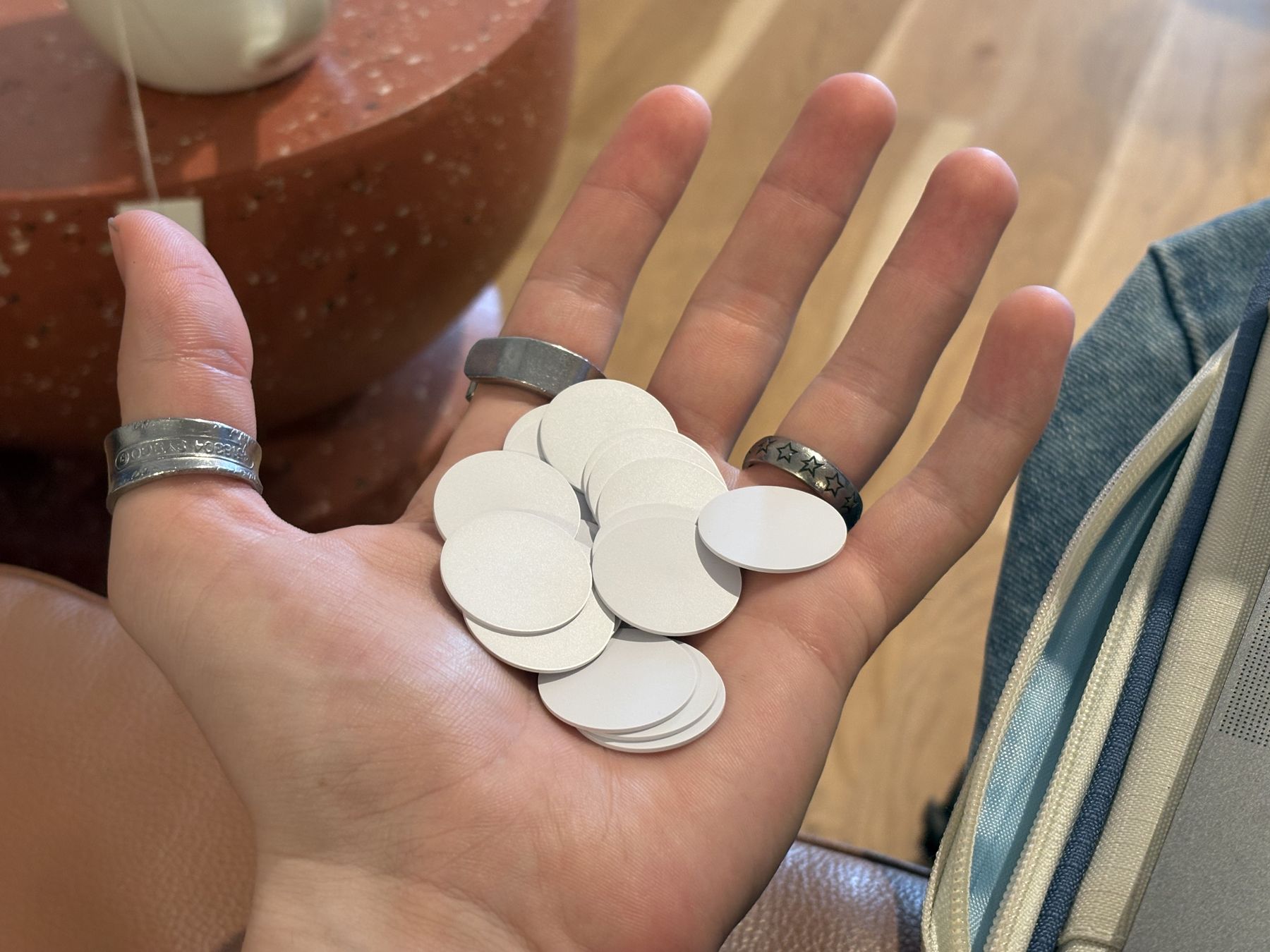 Palm holding a handful of round white NFC tags