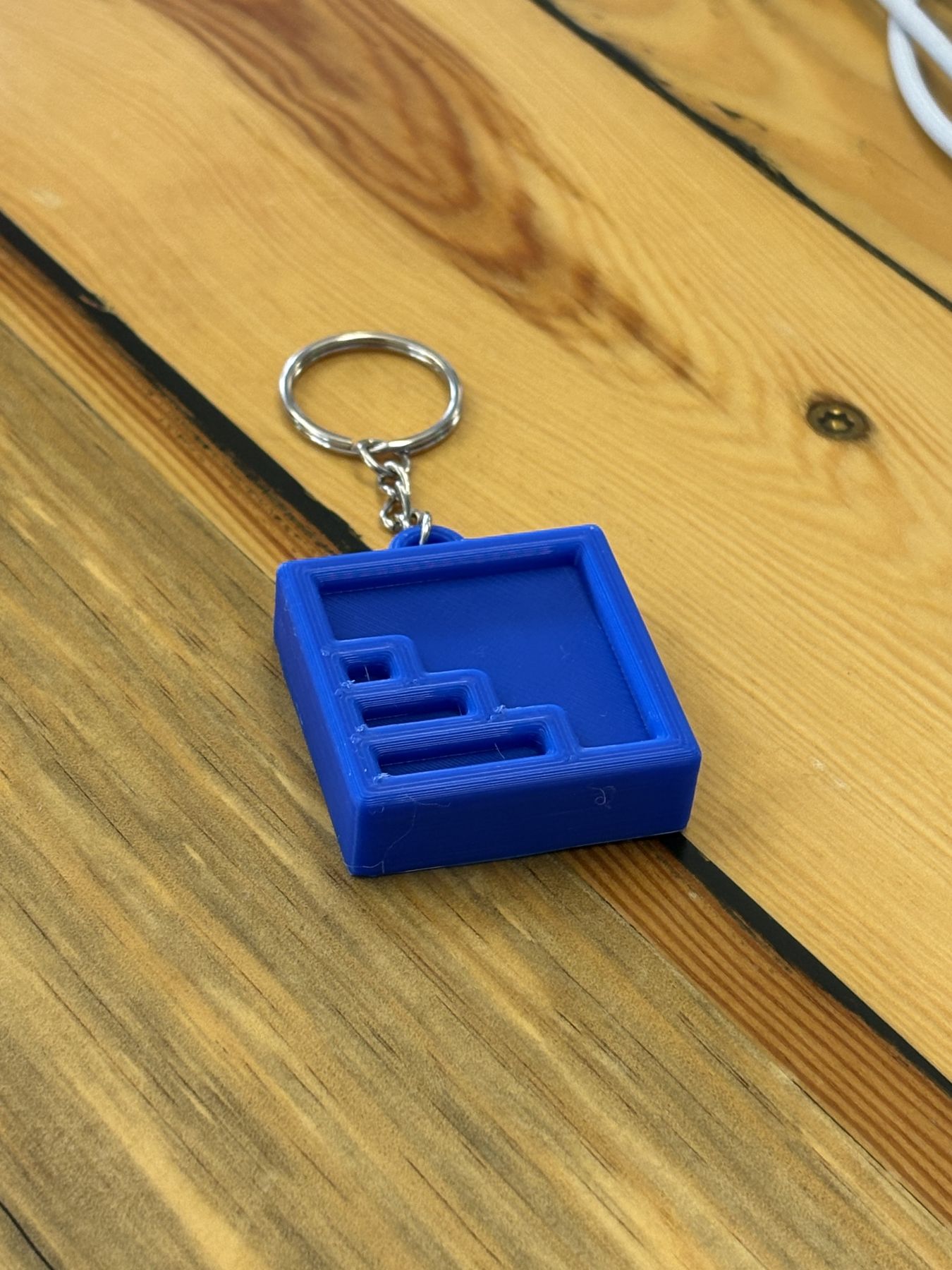 Finished blue square NODE keychain on a wood table