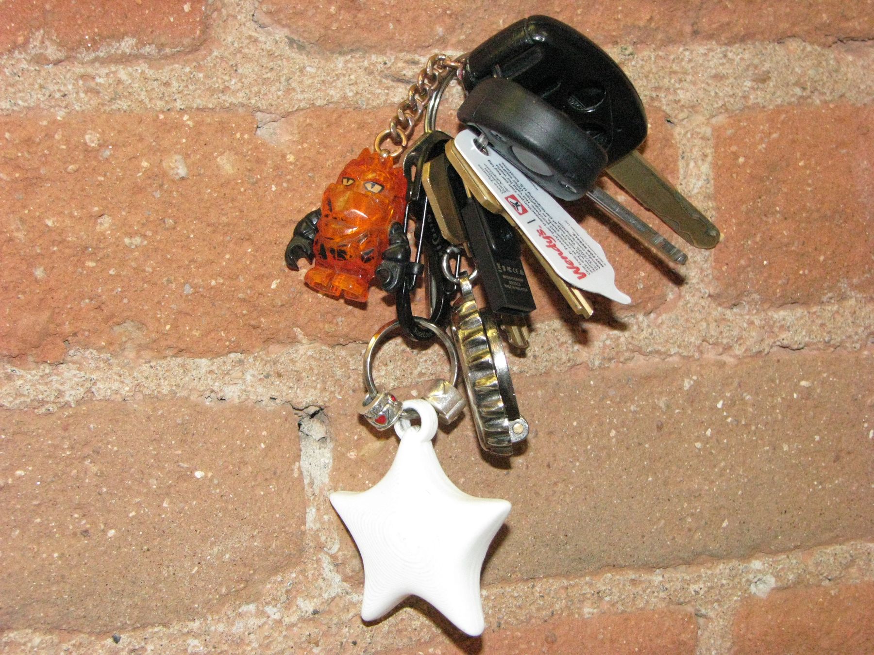 White star NODE charm on a keychain against brick
