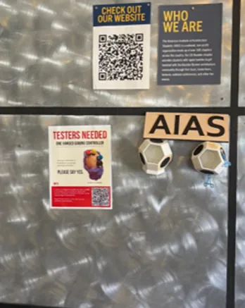 Recruitment flyer on a metal wall next to AIAS signage and soccer ball models